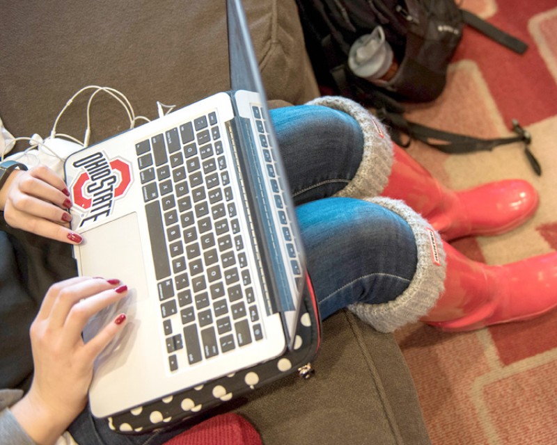 Hands using a laptop computer with an Ohio State sticker on it